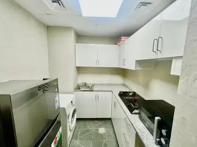 a small kitchen with white cabinets and a sink at Haifa building in Dubai