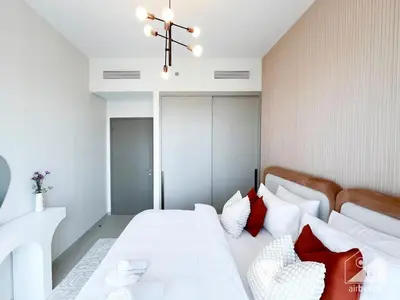 a bedroom with a white bed with red pillows at Luxury 1BR at Grande Downtown with Iconic Views in Dubai