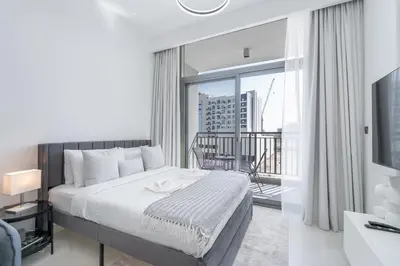 a bedroom with a large bed and a balcony at Bright & Modern Studio - Legacy By Sunrise - Arjan in Dubai