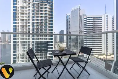 a table and chairs on a balcony with a view of a city at Vogue Business Bay Damac Maison Prive near Burj Khalifa and Dubai Mall, Studio Apartment with Balcony, Canal and City View, Access to all Amenities in Dubai