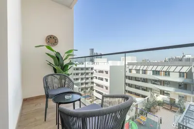 a balcony with two chairs and a clock on a building at Smartly Designed Studio in JVC in Dubai