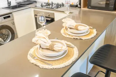 two plates and napkins on a kitchen counter with wine glasses at Smartly Designed Studio in JVC in Dubai