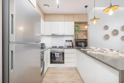 a kitchen with white cabinets and a stainless steel refrigerator at Smartly Designed Studio in JVC in Dubai