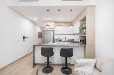 a kitchen and living room with a counter and chairs at Smartly Designed Studio in JVC in Dubai