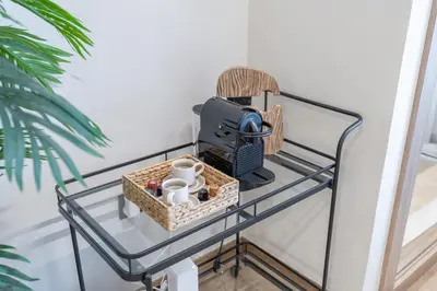 a glass shelf with a glass table with a camera and mugs at Smartly Designed Studio in JVC in Dubai