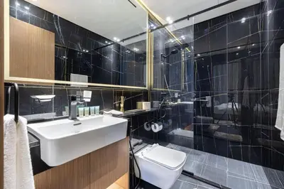 a black tiled bathroom with a sink and a toilet at Binghatti House in JVC - New Apartment in Dubai