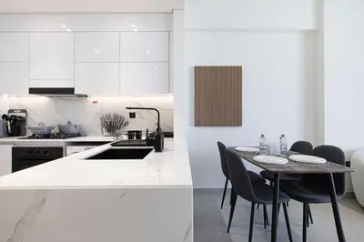 a kitchen with white cabinets and a table with chairs at Binghatti House in JVC - New Apartment in Dubai
