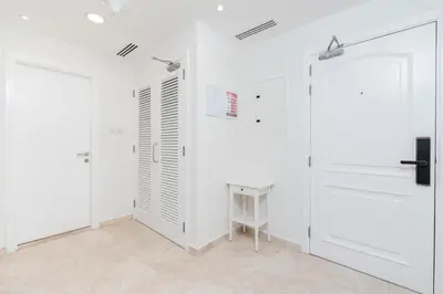 a white room with two doors and a table at Stylish 1-Bedroom with Breathtaking Views at Dubai Marina in Dubai