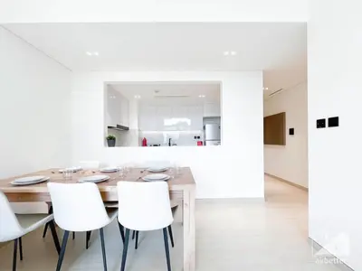a dining room with a wooden table and white chairs at Elegant 2 Bedroom Apartment -Binghatti Emerald JVC in Dubai