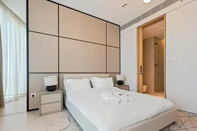 a bedroom with a large white bed with a large headboard at Werova - Sea View 3BR with Hotel Facilities Access in Dubai