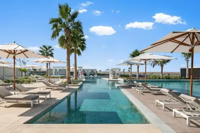 a swimming pool with lounge chairs and umbrellas at Werova - Sea View 3BR with Hotel Facilities Access in Dubai