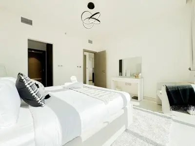 a white bedroom with a large bed and a chair at Azure - 1-Bed Luxury by Crystal Lagoon, Downtown in Dubai