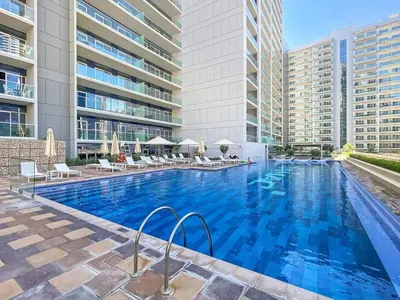 a large swimming pool with chairs and a building at Keyrock Living - Luxury 1BR with Lake View at Reva in Dubai