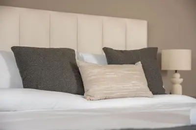 a white bed with two pillows on top of it at StayShort - Sleek Studio in Jumeirah Village Triangle in Dubai