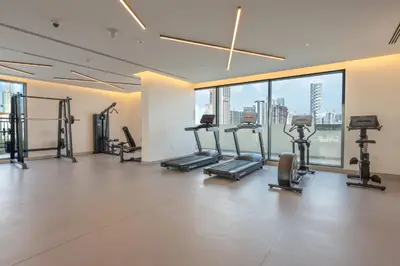 a gym with treadmills and ellipticals in a room with windows at StayShort - Sleek Studio in Jumeirah Village Triangle in Dubai