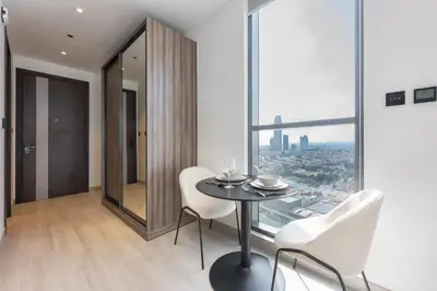 a dining room with a table and chairs and a window at StayShort - Sleek Studio in Jumeirah Village Triangle in Dubai
