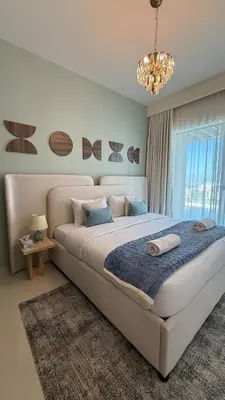 a bedroom with a large bed and a chandelier at Seaside Elegance 1BR at Emaar Beachfront in Dubai