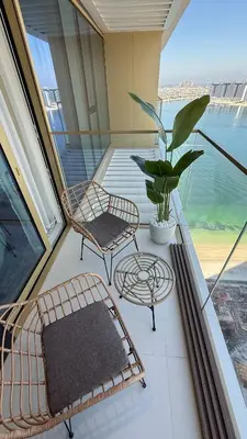 a balcony with a chair and a table and a plant at Seaside Elegance 1BR at Emaar Beachfront in Dubai
