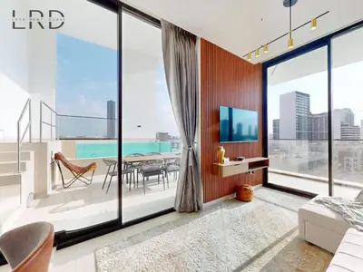 a bedroom with a balcony with a table and a television at Modern Smart Home 2BR with Private Pool in JVC in Dubai