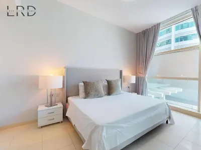 a bedroom with a white bed and a large window at Stylish 2BR Apartment Steps from Metro and Marina Mall in Dubai