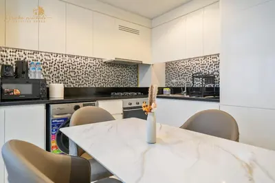a white kitchen with a table and chairs at Luxury Sea View High Floor 3Bhk in Dubai