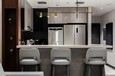 a kitchen with a bar with chairs and a refrigerator at SettlerHomes - Chic JLT 29 Floor Near Panoramic Lake in Dubai