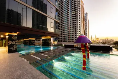 a pool with a purple umbrella and some buildings at SettlerHomes - Chic JLT 29 Floor Near Panoramic Lake in Dubai