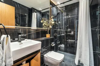 a black tiled bathroom with a sink and a shower at GuestReady - Sky-High Luxury with a Private Pool in Dubai
