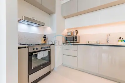 a kitchen with white cabinets and a stove at Dubai Harbour & Sea Views 1 BR Near Key Landmarks, Marina Vista T1, Emaar Beachfront by Deluxe Holiday Homes in Dubai