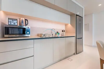a kitchen with white cabinets and a microwave at Dubai Harbour & Sea Views 1 BR Near Key Landmarks, Marina Vista T1, Emaar Beachfront by Deluxe Holiday Homes in Dubai