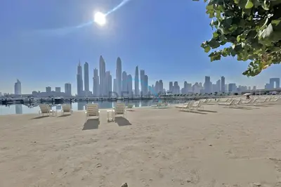 a group of chairs on a beach with a city at Dubai Harbour & Sea Views 1 BR Near Key Landmarks, Marina Vista T1, Emaar Beachfront by Deluxe Holiday Homes in Dubai