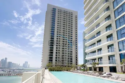a building with a swimming pool in front of a building at Dubai Harbour & Sea Views 1 BR Near Key Landmarks, Marina Vista T1, Emaar Beachfront by Deluxe Holiday Homes in Dubai
