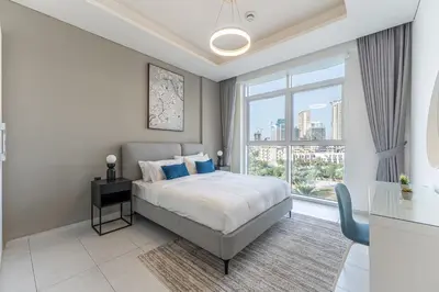 a bedroom with a bed and a large window at HAVN - New 1 Bedroom Apartment in Regent Court JVC in Dubai
