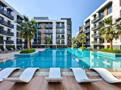 a swimming pool with lounge chairs and buildings at Sleek & Modern 1BR with Luxury Pool in JVC in Dubai