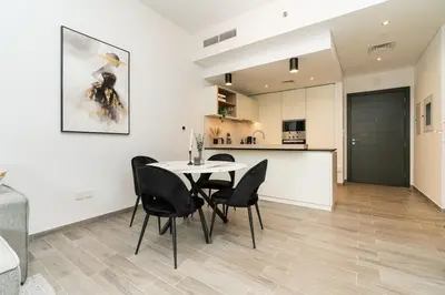 a dining room with a table and chairs and a kitchen at Sleek & Modern 1BR with Luxury Pool in JVC in Dubai
