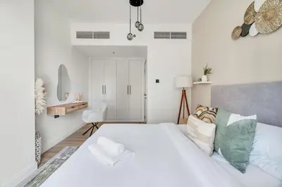 a white bedroom with a bed and a desk at GuestReady - Beautiful home in the JLT area in Dubai