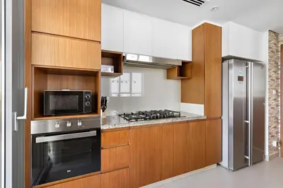 a kitchen with wooden cabinets and a stove and refrigerator at Stonetree - Spacious 2BR at Dubai Creek Residences in Dubai