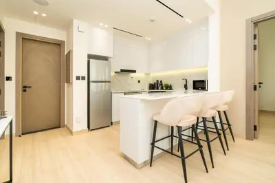 a kitchen with white cabinets and bar stools at Luxury 1BR Apartment in JVC with Stunning Pool in Dubai