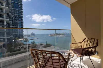 a balcony with two chairs and a view of the ocean at 2BD designed by Elie Saab with Private Beach Sea View by EE Holiday Homes in Dubai