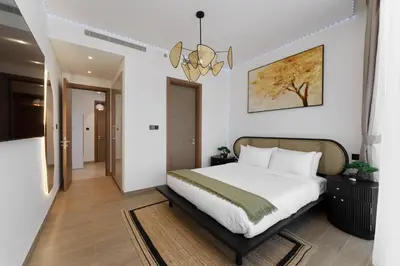 a bedroom with a bed and a chandelier at Daniels 1BR at Waves Grande In Sobha Hartland in Dubai