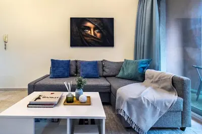 a living room with a couch and a painting on the wall at Spacious 1-BR Opposite Mall with Huge Pool & Gym in Dubai