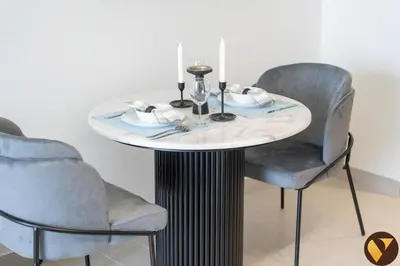 a table with two chairs and a table with plates and candles at Vogue JVC Binghatti Galaxy near Circle Mall, Studio Apartment with Balcony and City View, Access to all Amenities in Dubai