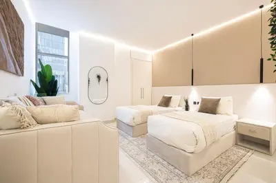 two beds in a white room with a couch at Downtown Views - For Big families & Groups - Up to 13 Guests - 6 min from Burj Khalifa in Dubai