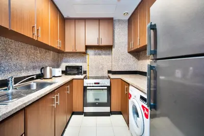 a kitchen with a refrigerator and a dishwasher at 1BR Stunning Canal & Burj view, Luxury Stay at Fairview Residency in Dubai