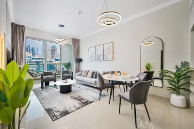 a living room with a couch and a table and chairs at 1BR Stunning Canal & Burj view, Luxury Stay at Fairview Residency in Dubai