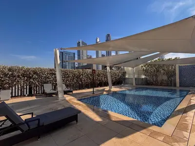 a swimming pool with a white umbrella and a building at Frank Porter - Downtown Views in Dubai