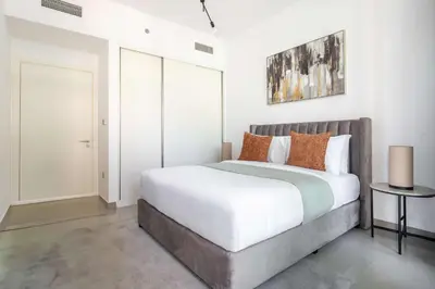 a bedroom with a bed with white sheets and orange pillows at Frank Porter - Beach Vista Tower 2 in Dubai
