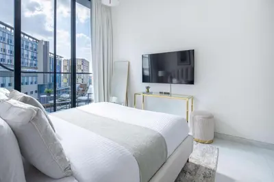 a white bedroom with a large bed and a flat screen tv at Frank Porter - Samana Park Views in Dubai