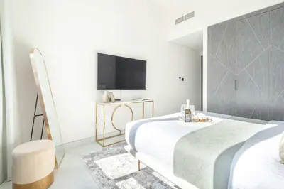 a white bedroom with a bed and a tv at Frank Porter - Samana Park Views in Dubai