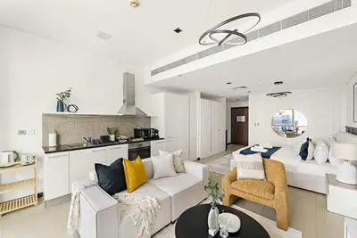a living room with a white couch and a kitchen at Silkhaus Comfy Studio in Liberty House DIFC Heart in Dubai